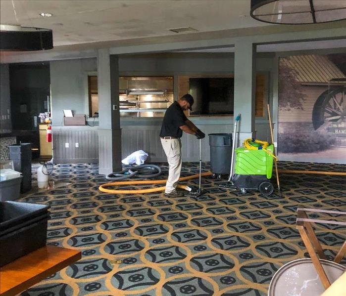 Worker using extracting vacuum on carpet floor, fire damage in a commercial building